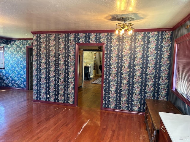 unfurnished dining area with wood-type flooring, crown molding, and an inviting chandelier