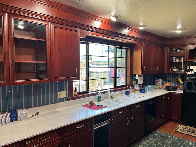 kitchen featuring sink, black appliances, a textured ceiling, and light hardwood / wood-style flooring