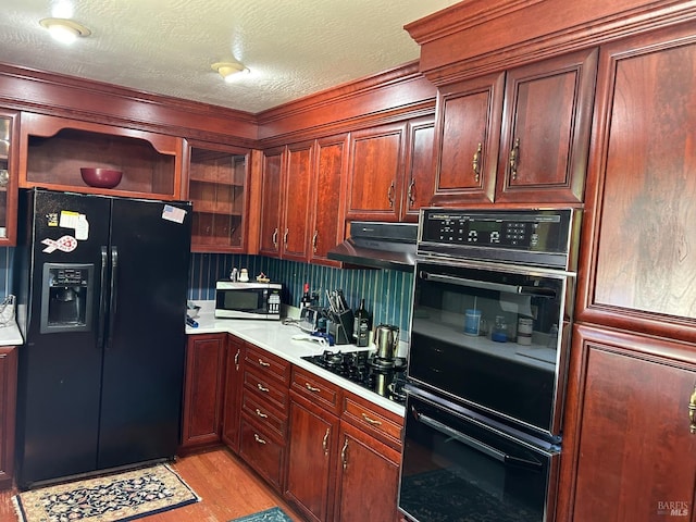 kitchen with black appliances, light wood-type flooring, a textured ceiling, and range hood