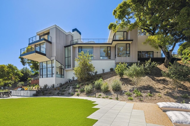 back of property with a yard, a patio area, and a balcony