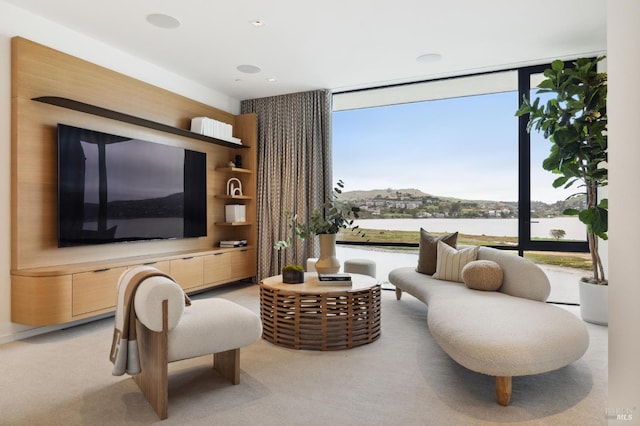 living area with a wall of windows, light colored carpet, and a water view