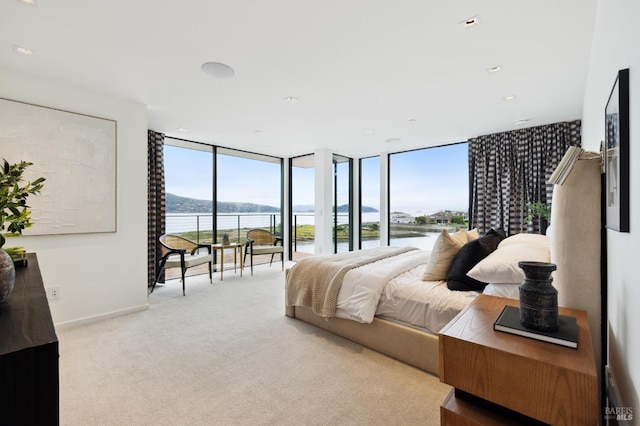 carpeted bedroom with a water view, floor to ceiling windows, and access to exterior