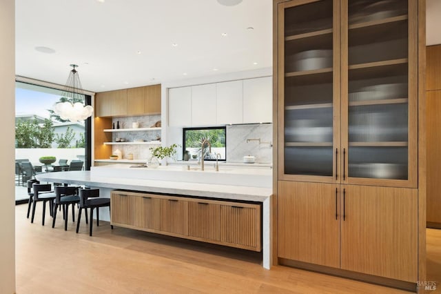 431 E Strawberry Dr, Mill Valley, CA 94941 - kitchen with decorative backsplash, a chandelier, pendant lighting, light wood-type flooring, and light stone counters