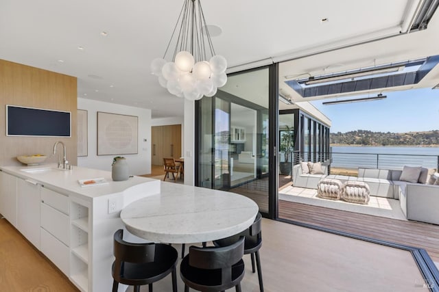 431 E Strawberry Dr, Mill Valley, CA 94941 - dining room with light wood-style floors, a chandelier, and a water view