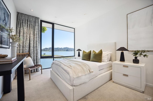 carpeted bedroom with a water view, expansive windows, and access to exterior