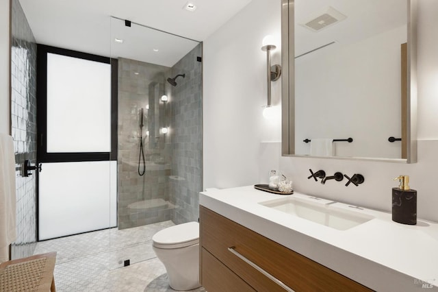 bathroom with vanity, tile patterned flooring, toilet, and tiled shower