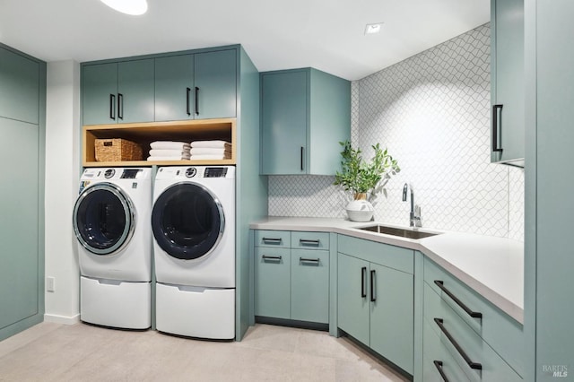 laundry room with cabinets, washer and clothes dryer, and sink