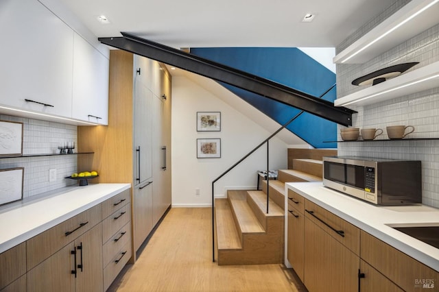 431 E Strawberry Dr, Mill Valley, CA 94941 - kitchen featuring stainless steel microwave, open shelves, light wood-style floors, decorative backsplash, and light countertops
