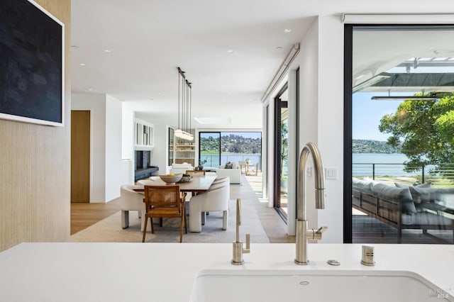 dining area with a water view, floor to ceiling windows, sink, and light wood-type flooring