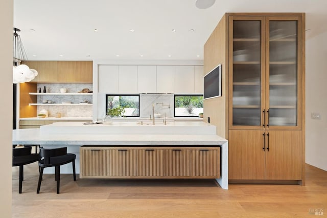 kitchen featuring radiator, pendant lighting, light hardwood / wood-style floors, decorative backsplash, and white cabinets