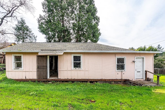 view of front of home featuring fence, a shingled roof, and a front yard