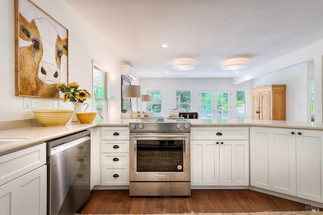 kitchen featuring dark wood-type flooring, white cabinetry, stainless steel appliances, a peninsula, and light countertops