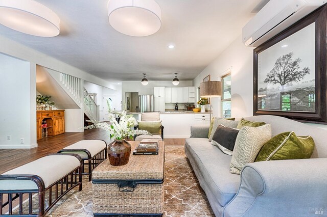 living room featuring an AC wall unit, wood finished floors, recessed lighting, stairway, and baseboards