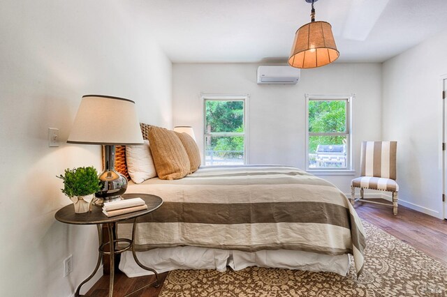 bedroom featuring wood-type flooring and an AC wall unit