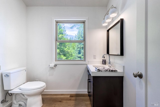 bathroom featuring wood-type flooring, plenty of natural light, vanity, and toilet