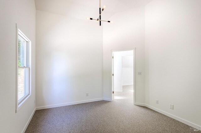 carpeted spare room with a wealth of natural light and a high ceiling