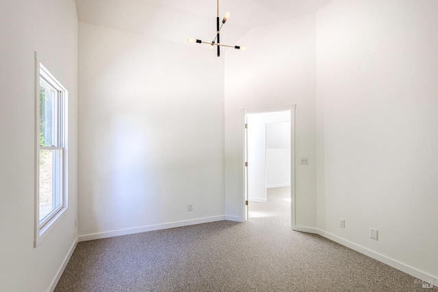 unfurnished room featuring a high ceiling, a notable chandelier, baseboards, and light carpet