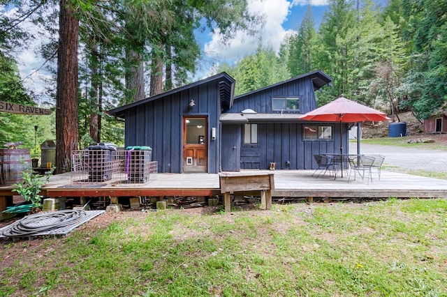 rear view of property featuring a lawn, board and batten siding, and a wooden deck