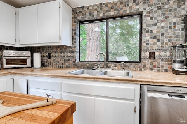 kitchen with a sink, tasteful backsplash, white cabinetry, light countertops, and dishwasher