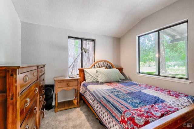 bedroom featuring a textured ceiling, lofted ceiling, and light carpet