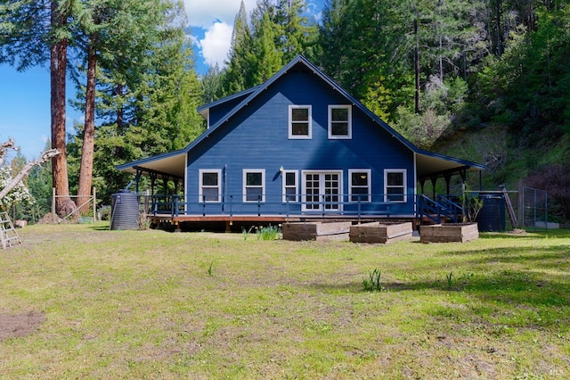 rear view of property with a deck, a carport, a lawn, and fence