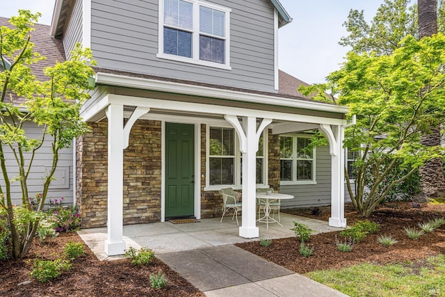 view of exterior entry with stone siding and a shingled roof