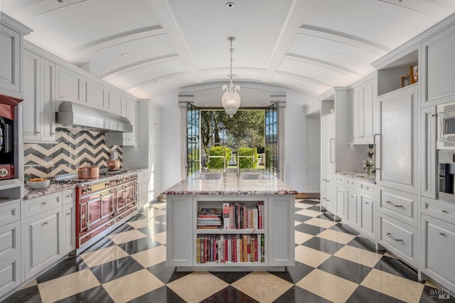 kitchen featuring wall chimney range hood, light tile flooring, lofted ceiling, and backsplash