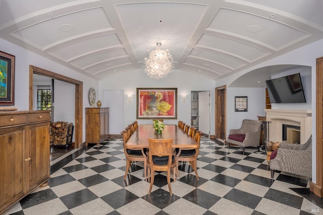 dining room featuring dark tile flooring, vaulted ceiling, and a chandelier