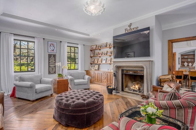 living room with crown molding, a fireplace, plenty of natural light, and parquet flooring