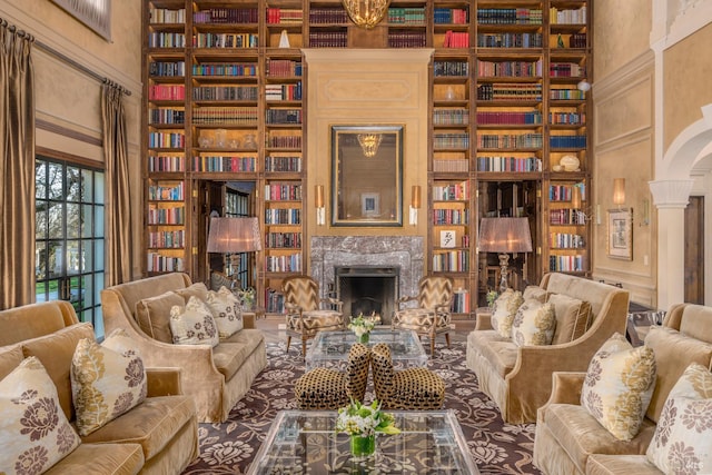 sitting room featuring ornate columns, a high end fireplace, and built in shelves