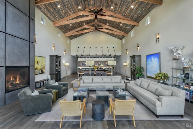 living room featuring high vaulted ceiling, hardwood / wood-style flooring, a large fireplace, and ceiling fan