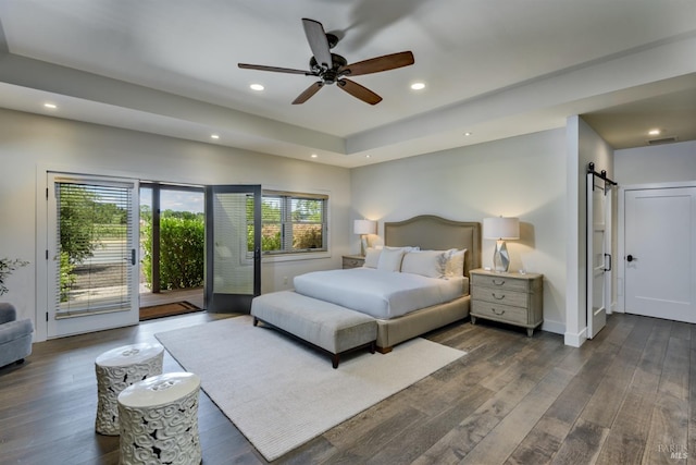 bedroom with dark wood-type flooring, a barn door, ceiling fan, and access to outside