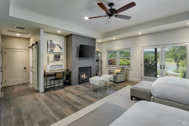 living room with a barn door, ceiling fan, dark hardwood / wood-style floors, and a fireplace