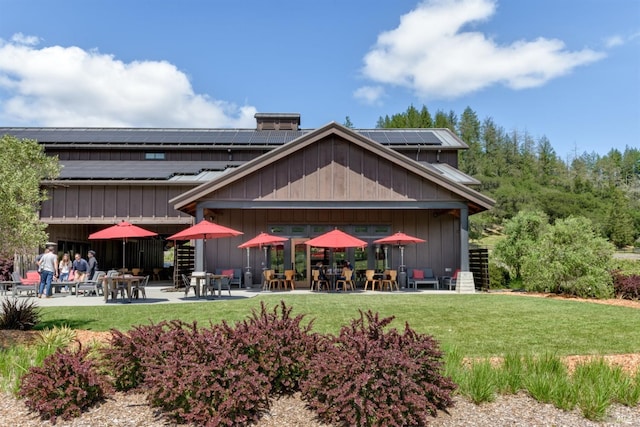 rear view of house featuring a patio area, solar panels, and a lawn