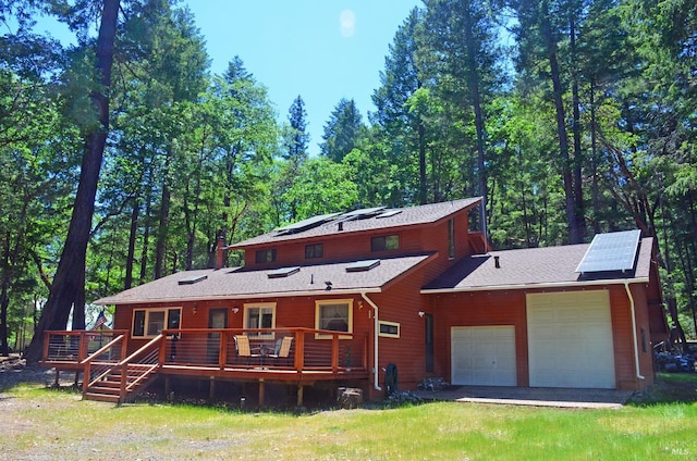 view of front of house with a garage, a wooden deck, and solar panels