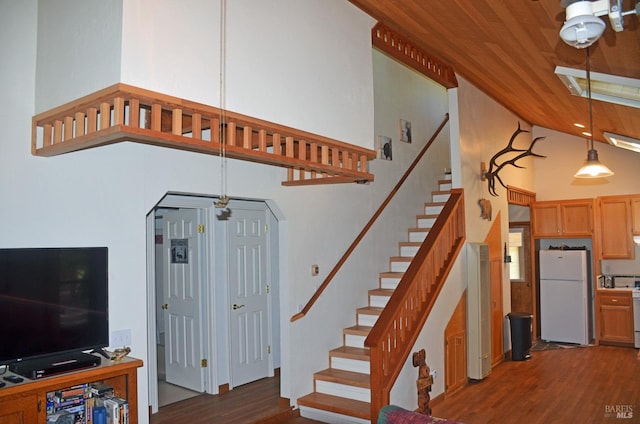 stairs featuring a towering ceiling and dark hardwood / wood-style floors