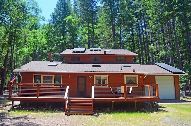 rear view of property with a garage and a wooden deck