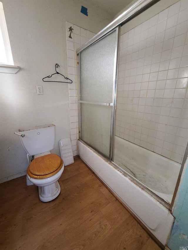 bathroom with combined bath / shower with glass door, toilet, and hardwood / wood-style floors