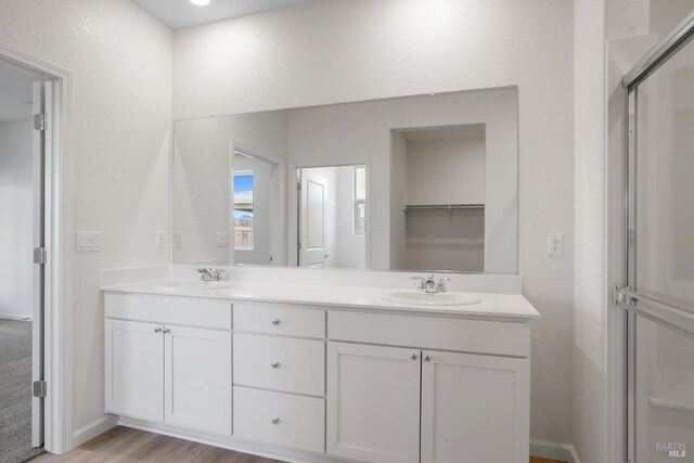 bathroom with double vanity, wood finished floors, and a sink