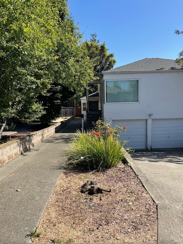 view of side of home with concrete driveway, an attached garage, and stucco siding