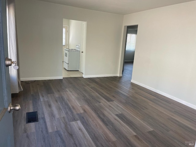 spare room featuring a healthy amount of sunlight, visible vents, and dark wood finished floors