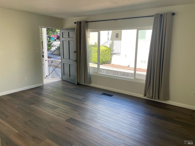 spare room featuring dark wood-style floors, baseboards, and visible vents