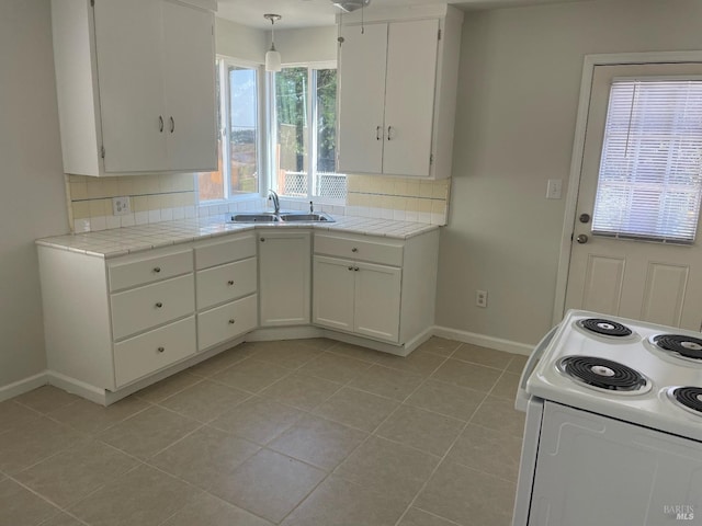 kitchen featuring tile countertops, a sink, and white cabinets
