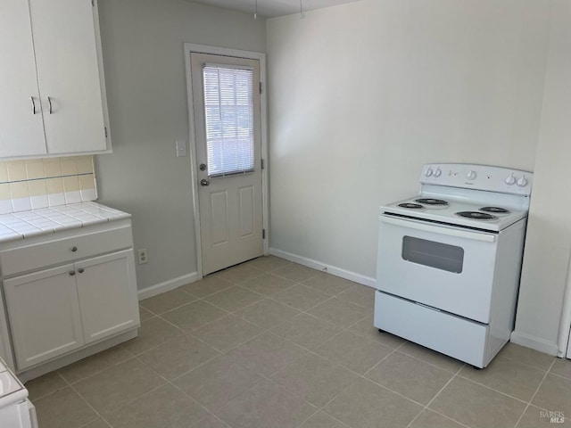 kitchen featuring white electric stove, tile countertops, white cabinetry, baseboards, and backsplash