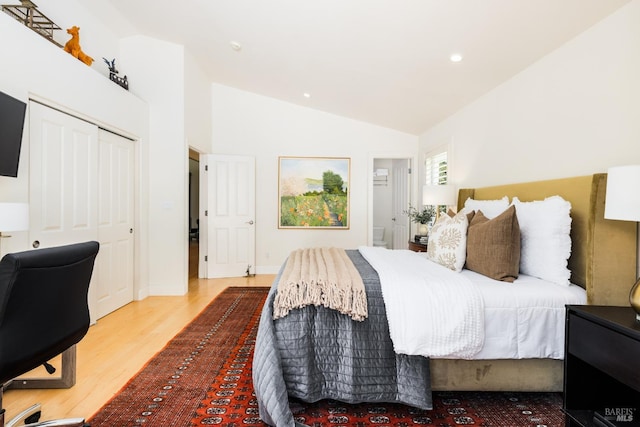 bedroom with wood-type flooring, vaulted ceiling, and a closet