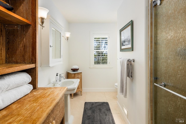 bathroom featuring toilet, tile patterned floors, walk in shower, and sink