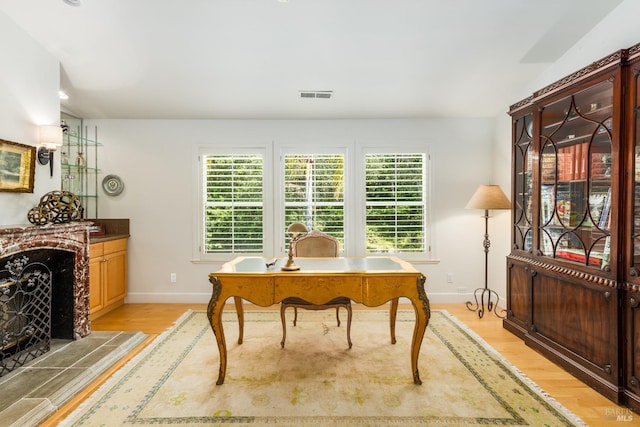 office area featuring a tile fireplace and light hardwood / wood-style floors