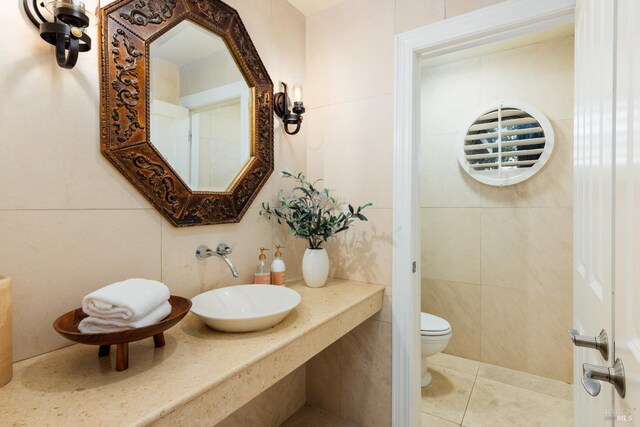 bathroom with sink, tile patterned flooring, tile walls, and toilet