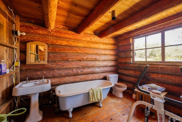 bathroom with a freestanding tub, hardwood / wood-style flooring, beamed ceiling, toilet, and rustic walls