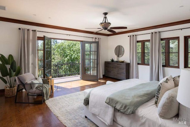 bedroom with ornamental molding, wood-type flooring, multiple windows, and access to exterior